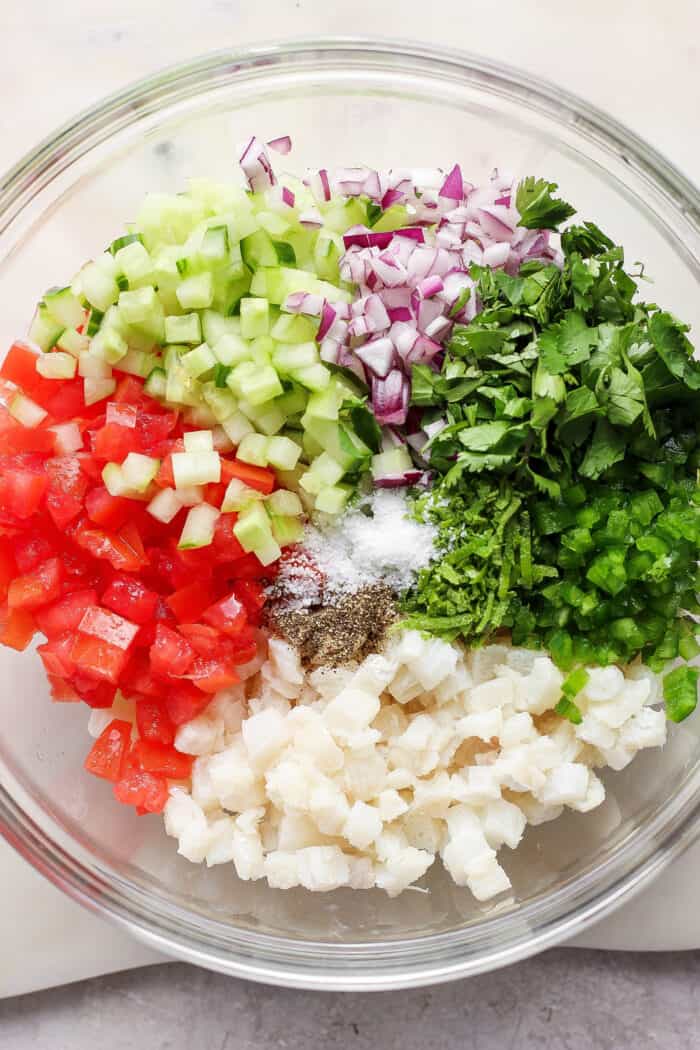 This refreshing Classic Ceviche recipe marinates fresh fish in lime and orange juices, then adds a mix of fresh veggies and a bit of jalapeno. Vegetables are added to the bowl of ceviche.