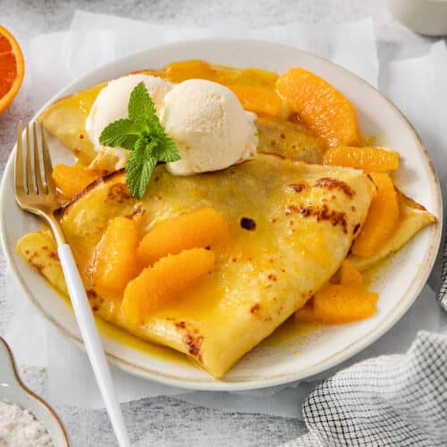 A fork rests on the side of a plate of crepes Suzette.
