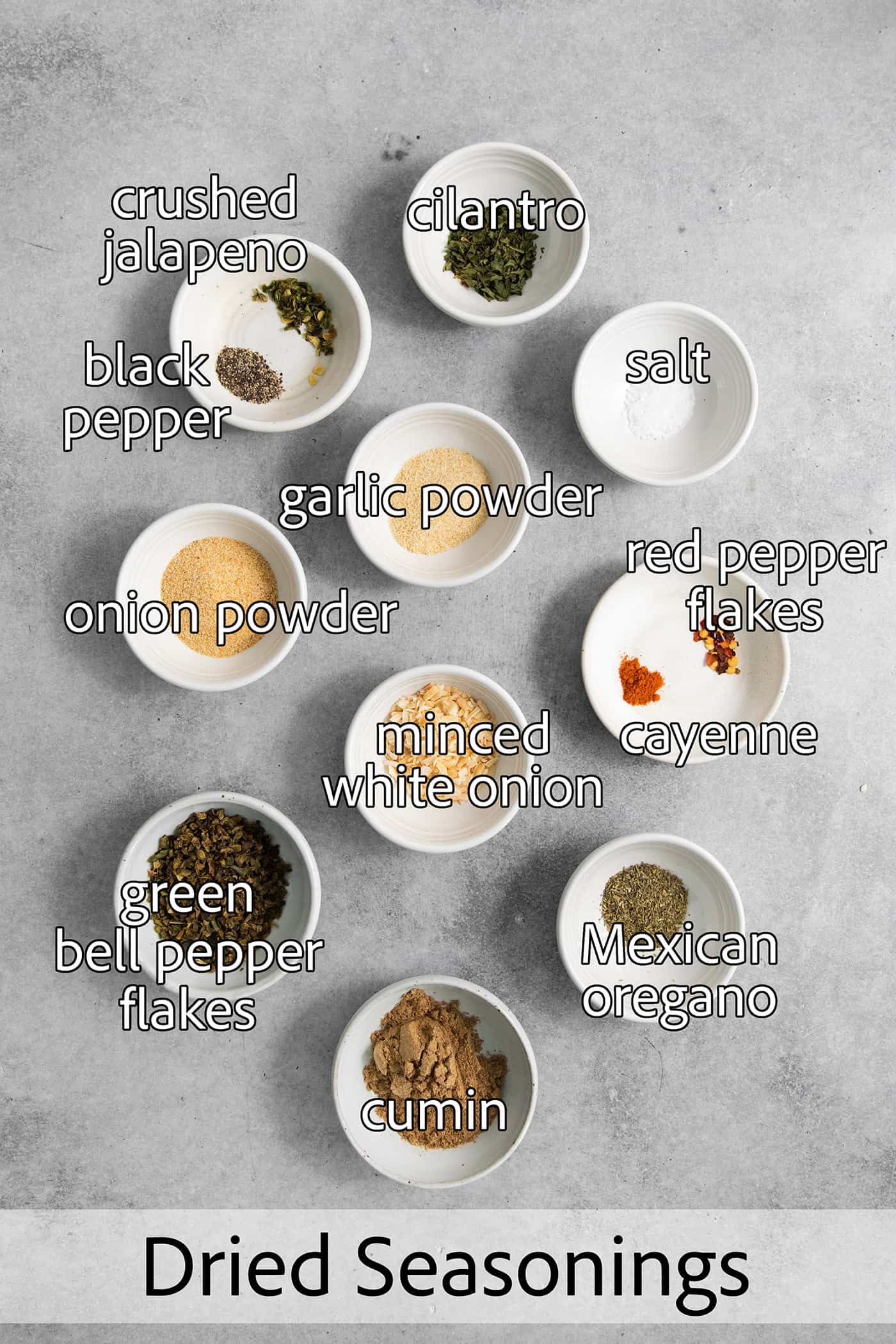 Homemade Green Taco Seasoning is so easy to DIY! It's flavorful, not too spicy, and is perfect in tacos, nachos, quesadillas and more. All of the spices needed for green taco seasoning are shown labelled and portioned out: onion and garlic powder, dried onion, salt and pepper, dried peppers, dried cilantro.