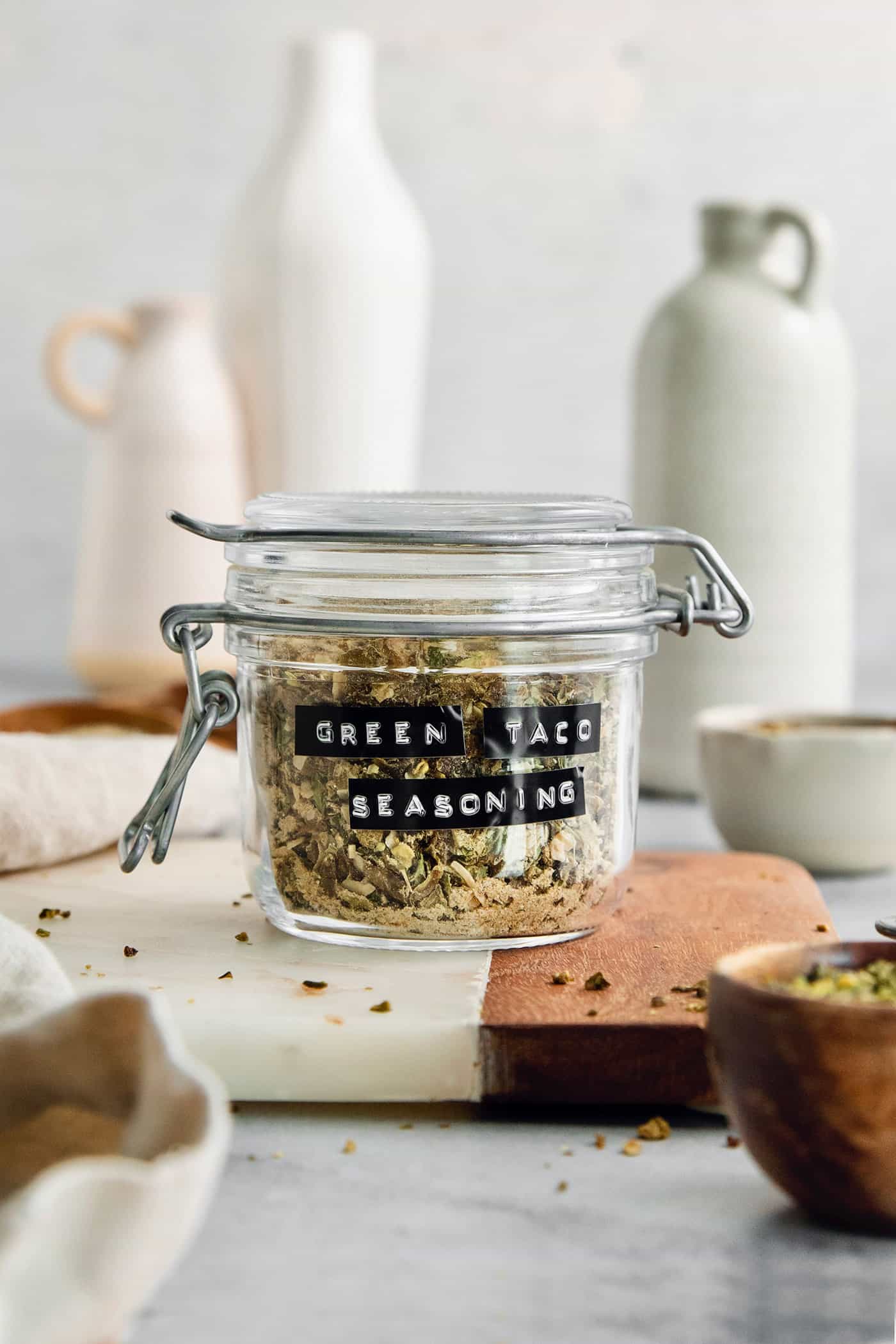 Homemade Green Taco Seasoning is so easy to DIY! It's flavorful, not too spicy, and is perfect in tacos, nachos, quesadillas and more. A labeled glass jar of green taco seasoning on a cutting board.