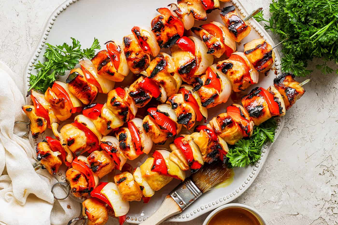 A serving platter of honey mustard chicken kabobs on skewers.