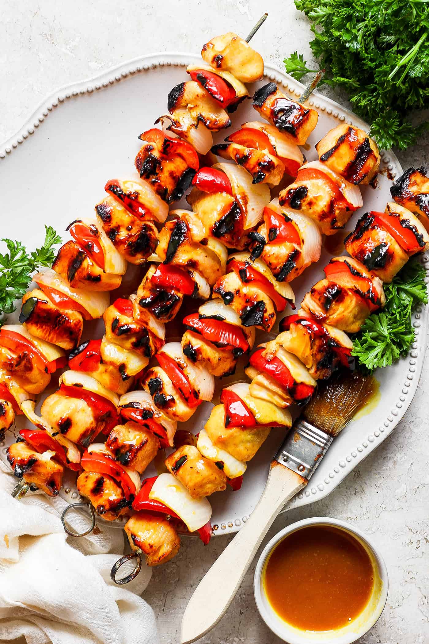 A serving platter of honey mustard chicken kabobs on skewers.