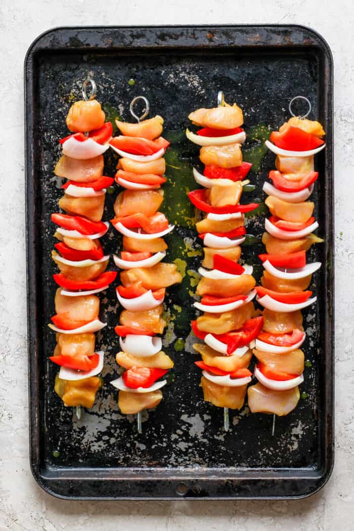 Four honey mustard chicken kabobs on a grill.