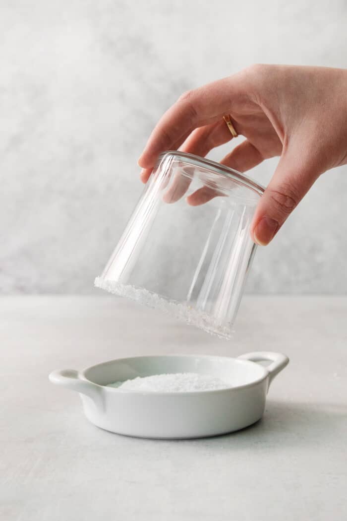 This Classic Margarita recipe makes the perfect tequila cocktail! Learn how to make a margarita that's always crisp, cold, and refreshing. A hand dips a glass into a dish of salt.