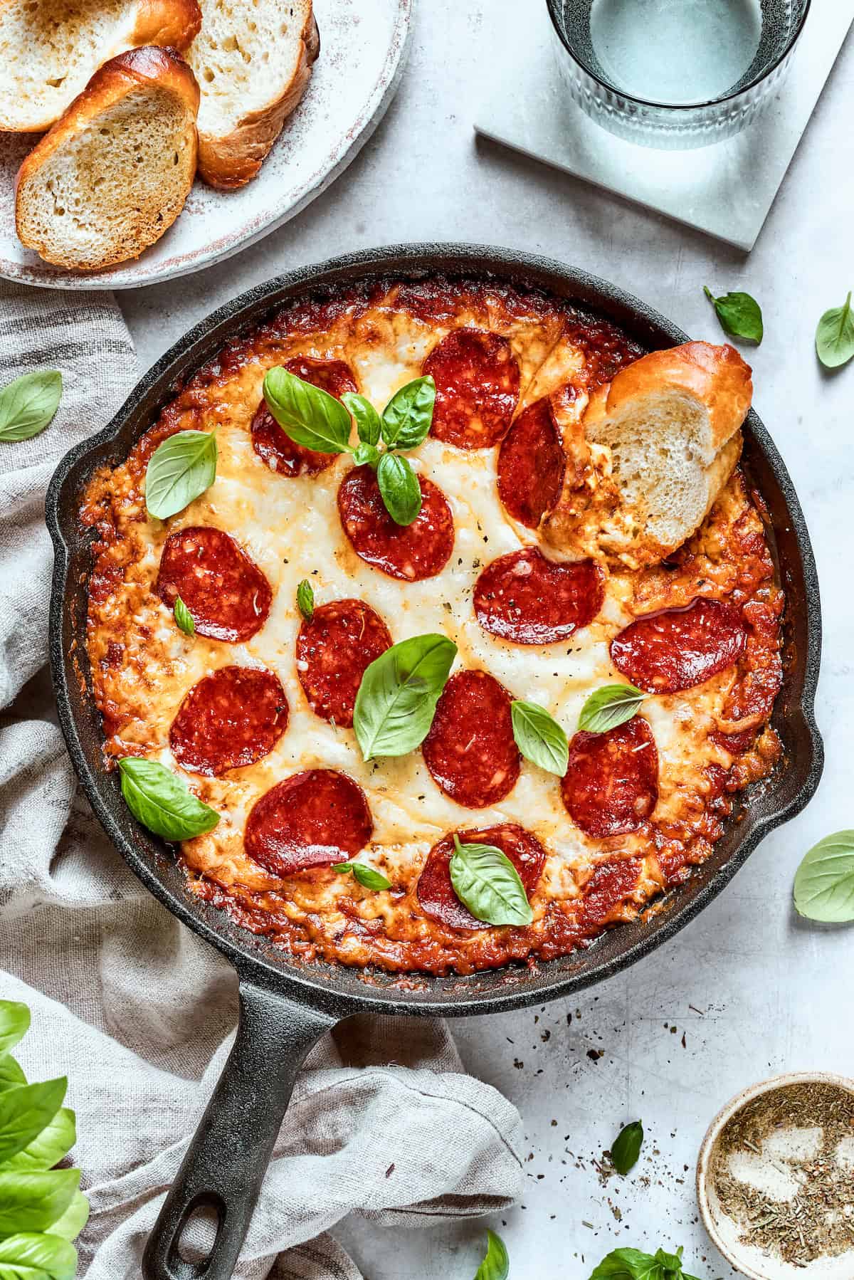 A slice of bread is dipped into a pan of pizza dip.