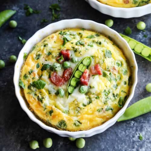 A ramekin of baked eggs is topped with peas.