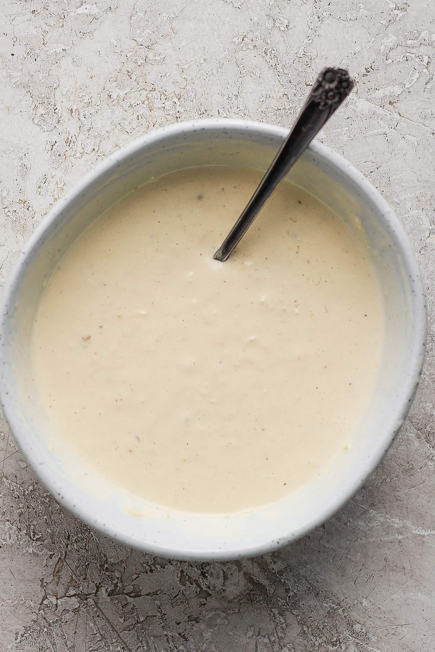This gorgeously rich and creamy homemade Caesar Dressing recipe is perfect for making a classic Caesar salad. Takes minutes to make. The caesar dressing is shown in a white bowl with a spoon.