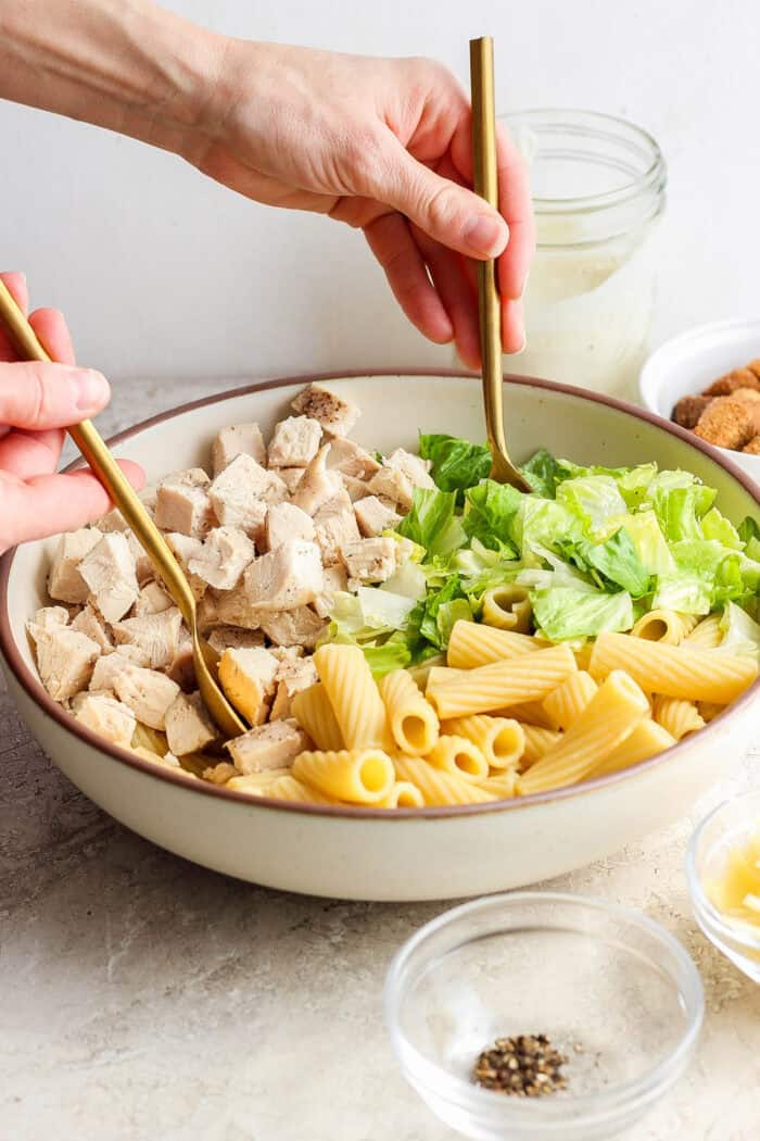 The Caesar chicken pasta salad is tossed to combine.
