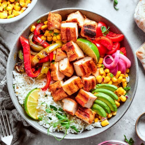 overhead photo of a fajita bowl with rice, chicken, corn salsa, pickled red onions, peppers, and avocado