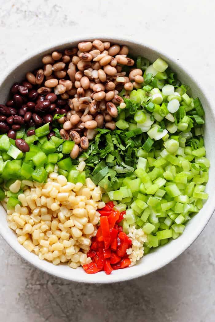 Cowboy caviar ingredients are added to a bowl, unmixed.