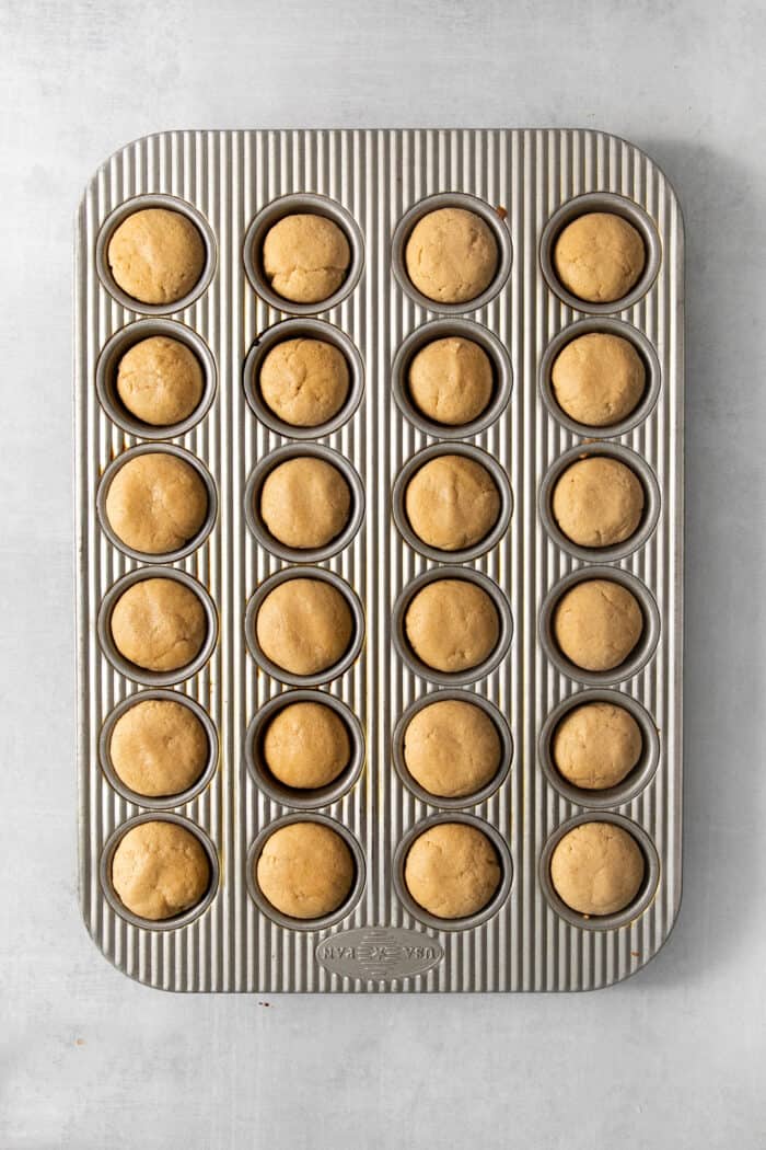 These Peanut Butter Cup Cookies feature soft and chewy peanut butter cookies stuffed with a gooey, chocolatey Reese's cup. The peanut butter cup cookies in the tin after being baked.