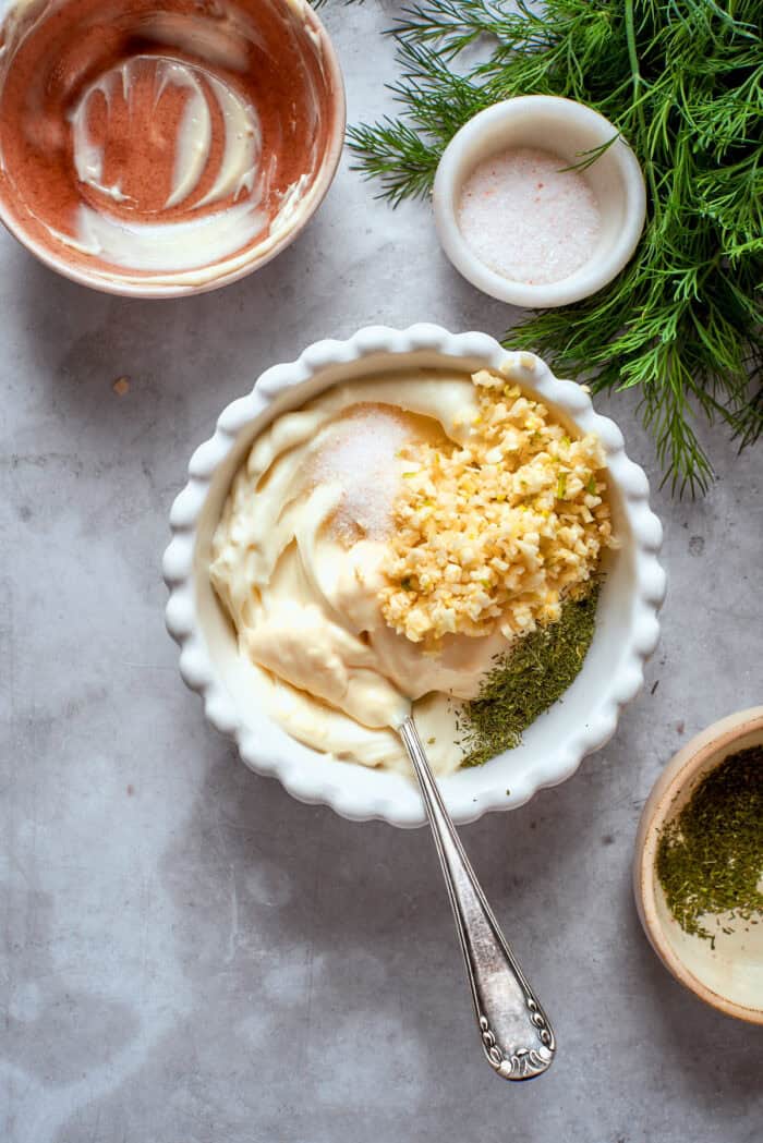 Creamy, crunchy, and puckery dill Pickle Pizza is a fun twist on classic pizza with white sauce, fresh and shredded mozzarella, dill, and plenty of pickles. The sauce ingredients are added to a bowl.