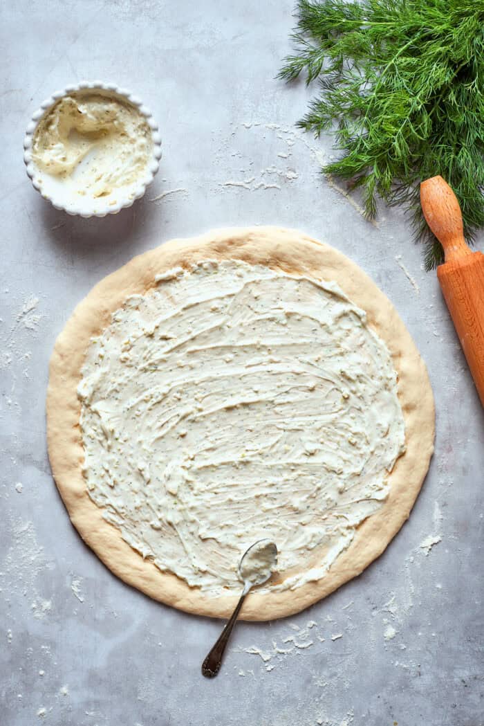 The white sauce is spread evenly on the pizza dough.