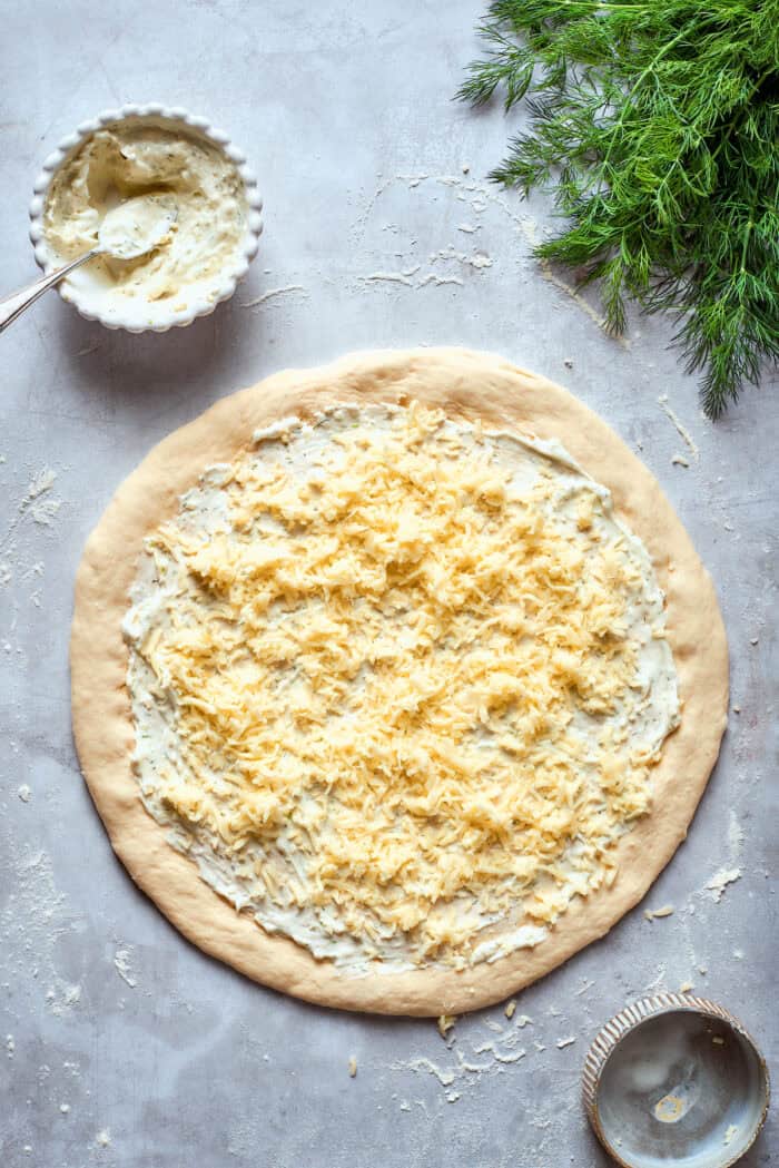 Creamy, crunchy, and puckery dill Pickle Pizza is a fun twist on classic pizza with white sauce, fresh and shredded mozzarella, dill, and plenty of pickles. Shredded mozzarella is added to the pizza.