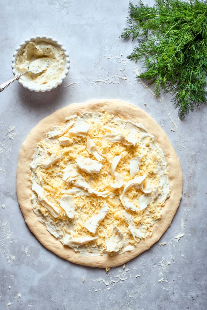 Creamy, crunchy, and puckery dill Pickle Pizza is a fun twist on classic pizza with white sauce, fresh and shredded mozzarella, dill, and plenty of pickles. Fresh mozzarella pieces are added to the top of the pizza.