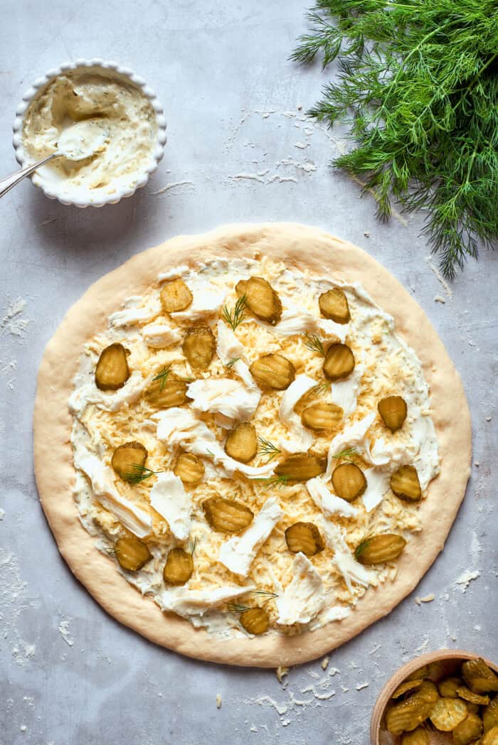 Creamy, crunchy, and puckery dill Pickle Pizza is a fun twist on classic pizza with white sauce, fresh and shredded mozzarella, dill, and plenty of pickles. The pizza is topped with pickles.