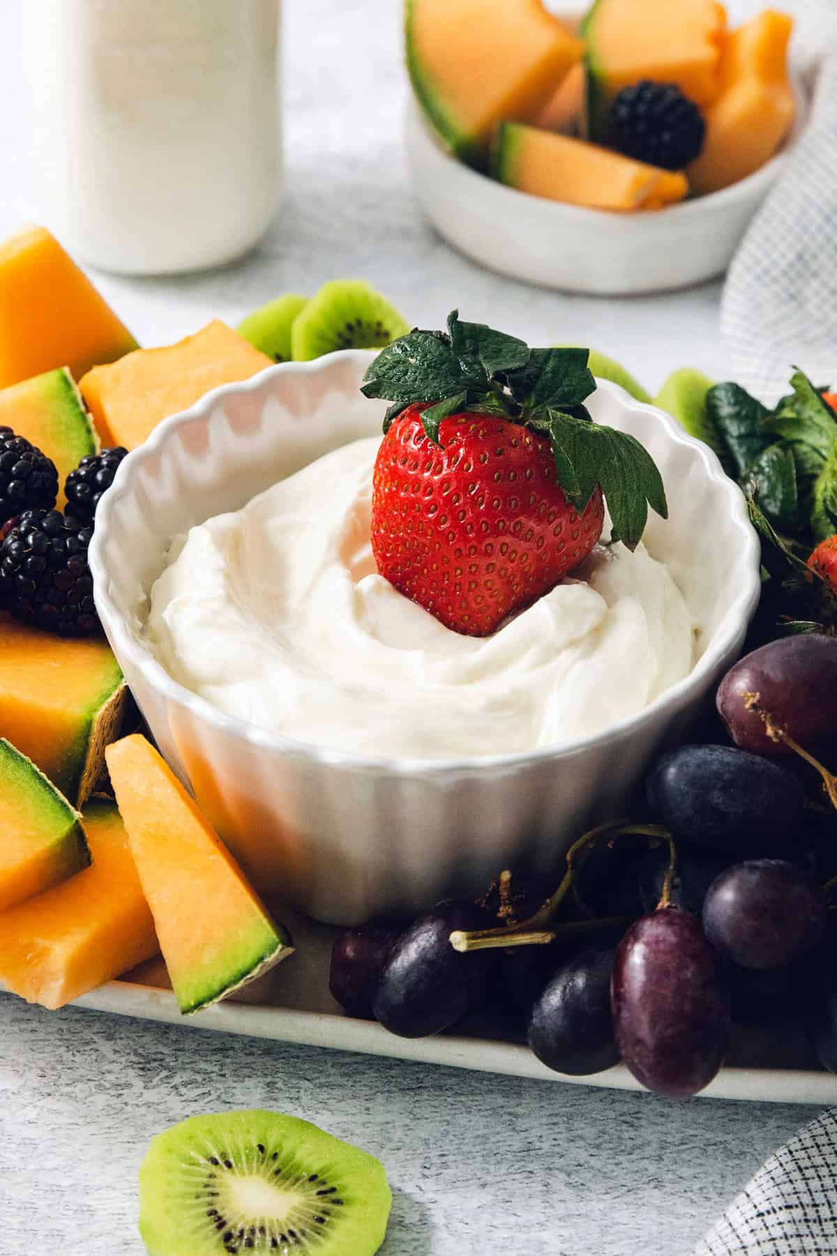 A strawberry is dipped into a bowl of fruit dip.
