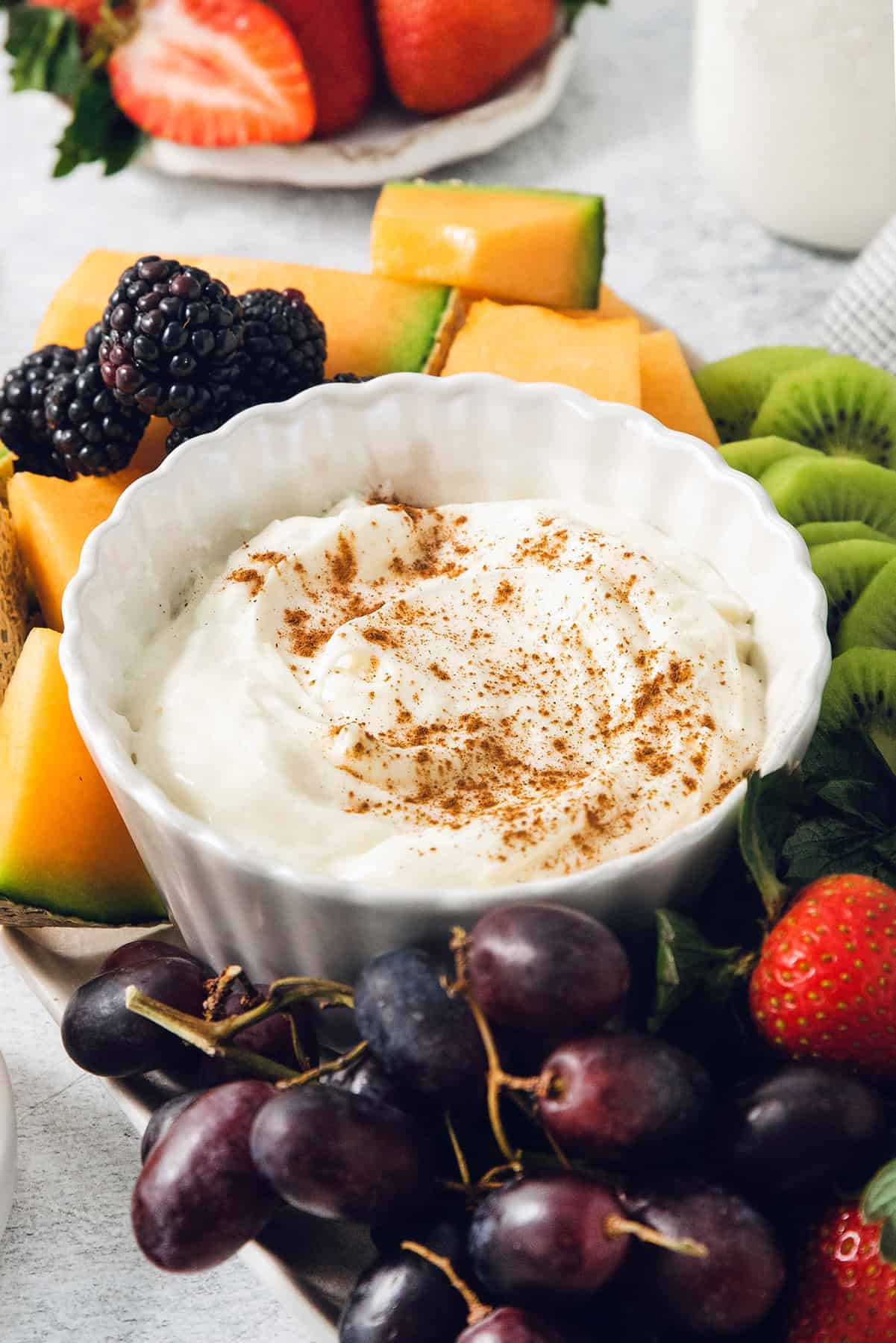 This 2-ingredient Fruit Dip is the perfect fluffy and creamy dessert dip featuring tangy cream cheese swirled with marshmallow creme. A bowl of fruit dipped is topped with cinnamon.