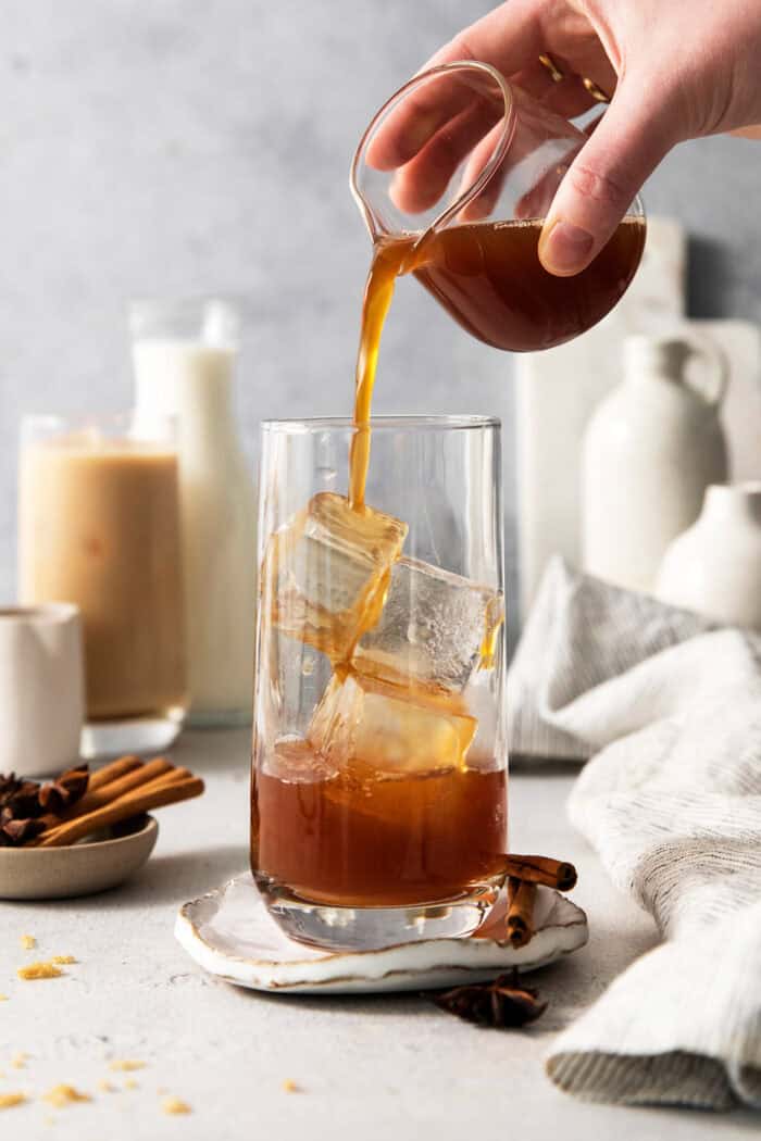 This easy Iced Chai Latte recipe is the perfect refreshing drink, featuring crisp black tea, warm spices, and a hint of brown sugar. Chai concentrate is poured into a glass wtih ice.