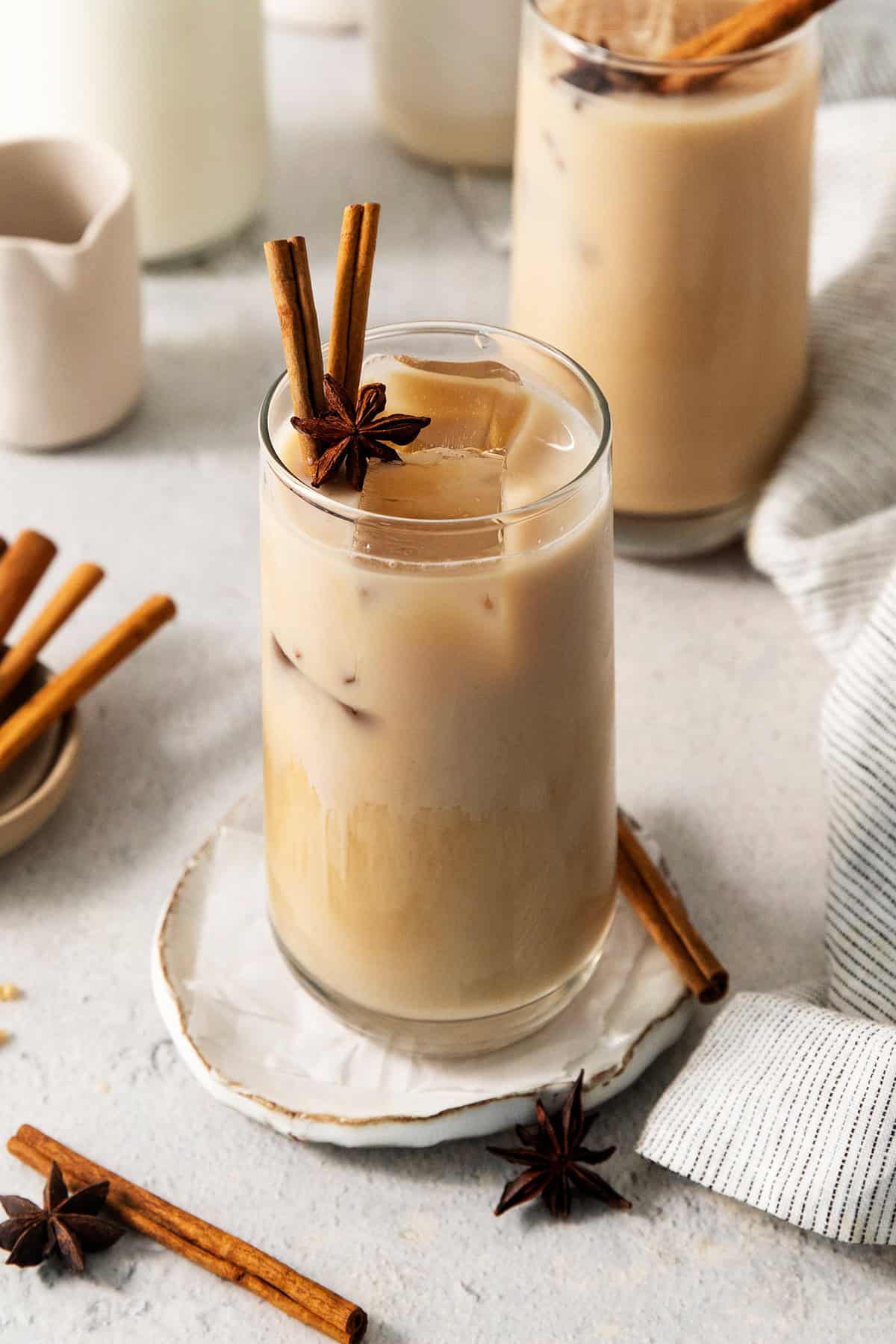 This easy Iced Chai Latte recipe is the perfect refreshing drink, featuring crisp black tea, warm spices, and a hint of brown sugar. Cinnamon sticks and star anise garnish tall glasses of iced chai latte.
