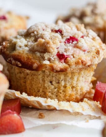 side view of rhubarb muffins, one with the paper liner pulled away from the muffin