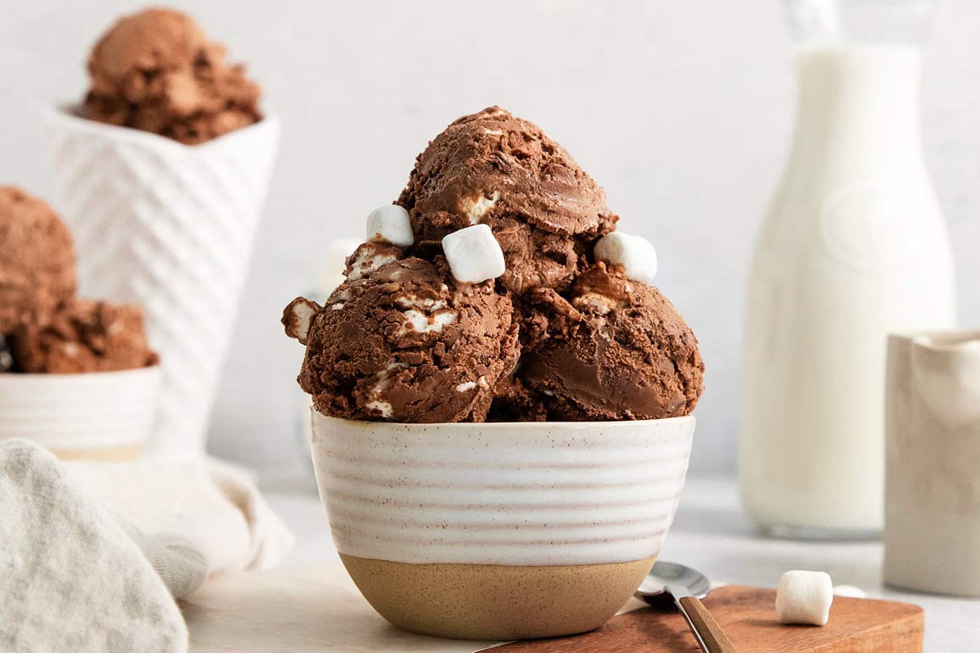A few mini marshmallows adorn scoops of rocky road ice cream in a bowl.