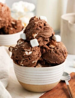 A few mini marshmallows adorn scoops of rocky road ice cream in a bowl.