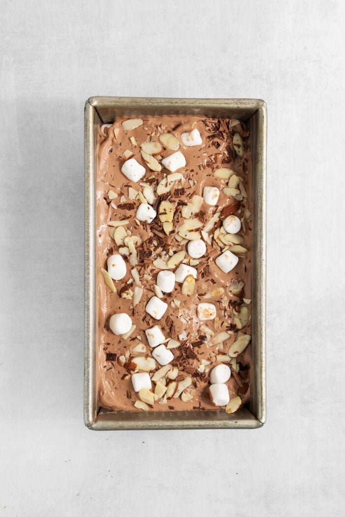 Rocky Road Ice Cream stars a creamy chocolate custard base that's loaded with almonds, marshmallows, and even more chocolate! The ice cream is placed in a metal loaf pan and topped with mini marshmallows.