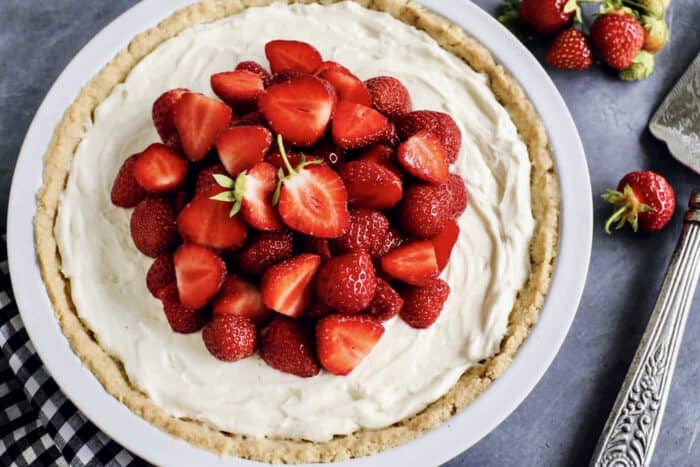 This Strawberry Cream Cheese Pie piles a fluffy cream cheese layer on a crisp shortbread cookie crust along with a fresh strawberry topping. strawberry cream cheese pie in a white pie plate