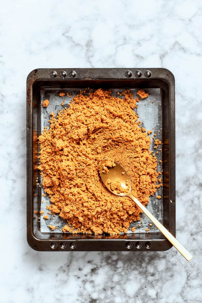 Graham cracker crust is spread into a pan.