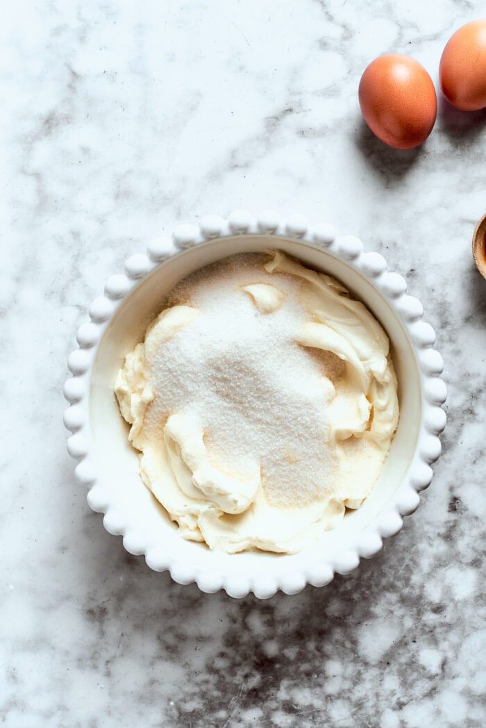 Sugar and cream cheese are combined in a white bowl.