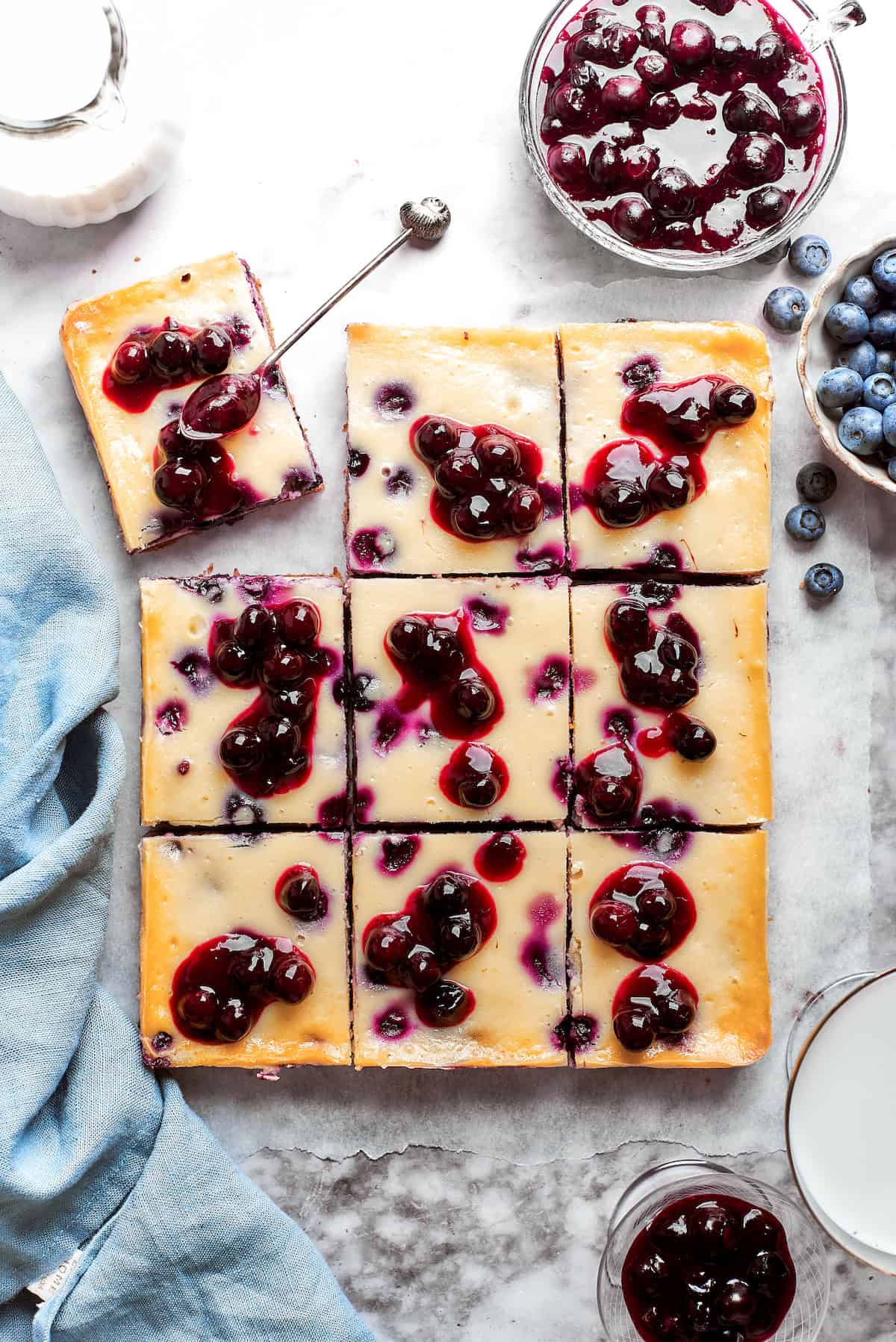Nine pieces of blueberry cheesecake bars are shown cut into pieces.