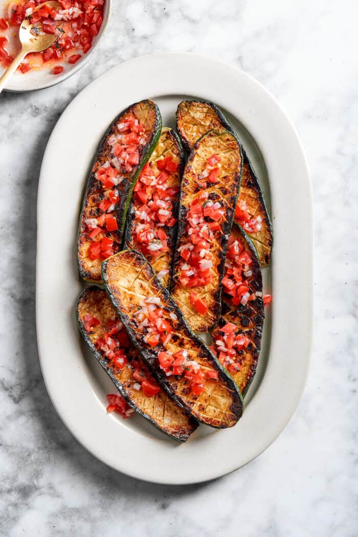 A platter of Thomas Keller zucchini is topped with tomato sauce.
