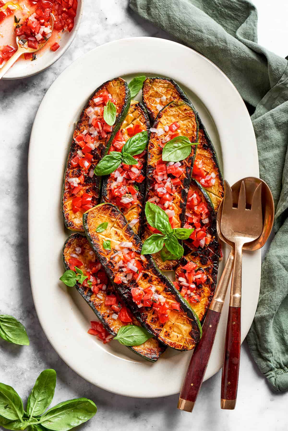 Serving spoons rest alongside a platter of Thomas Keller zucchini.