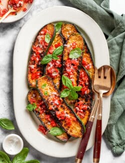 Serving spoons rest alongside a platter of Thomas Keller zucchini.