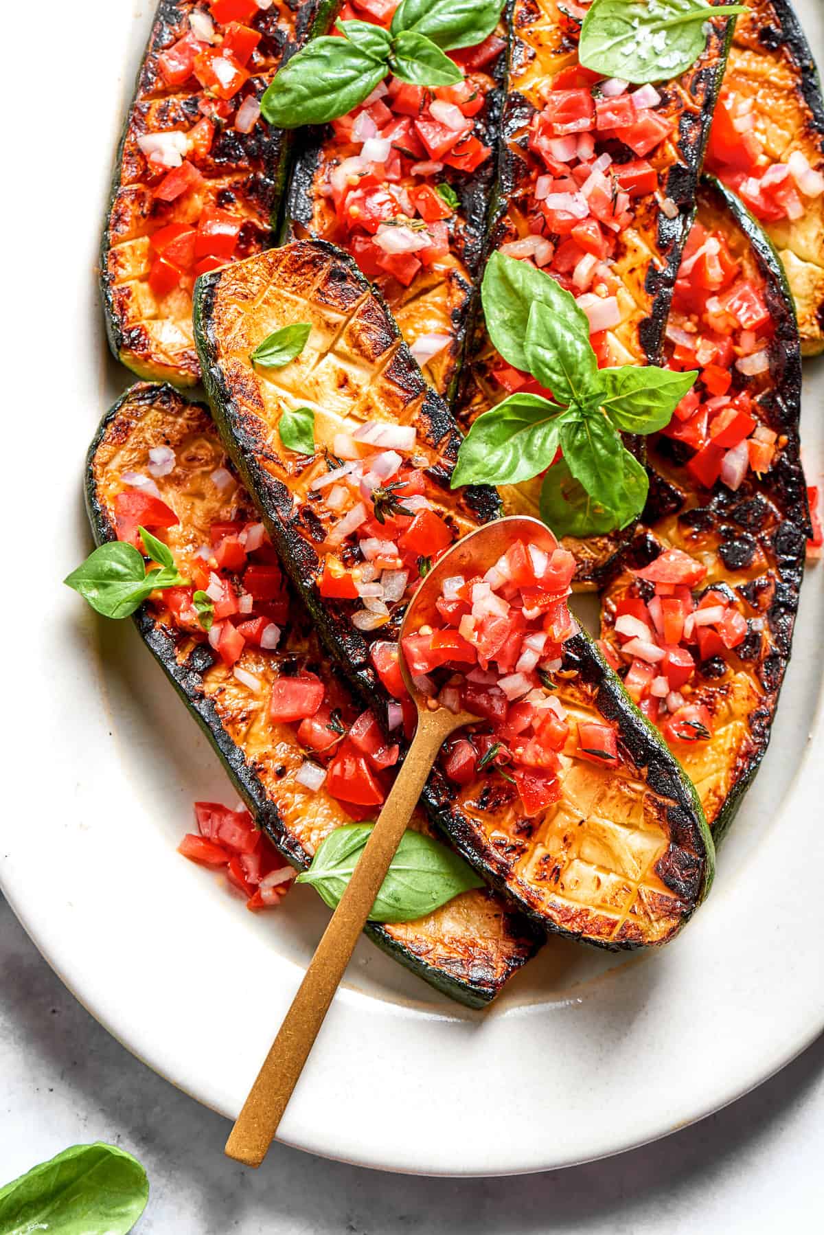 A serving utensil rests on top of a platter of Thomas Keller Zucchini.