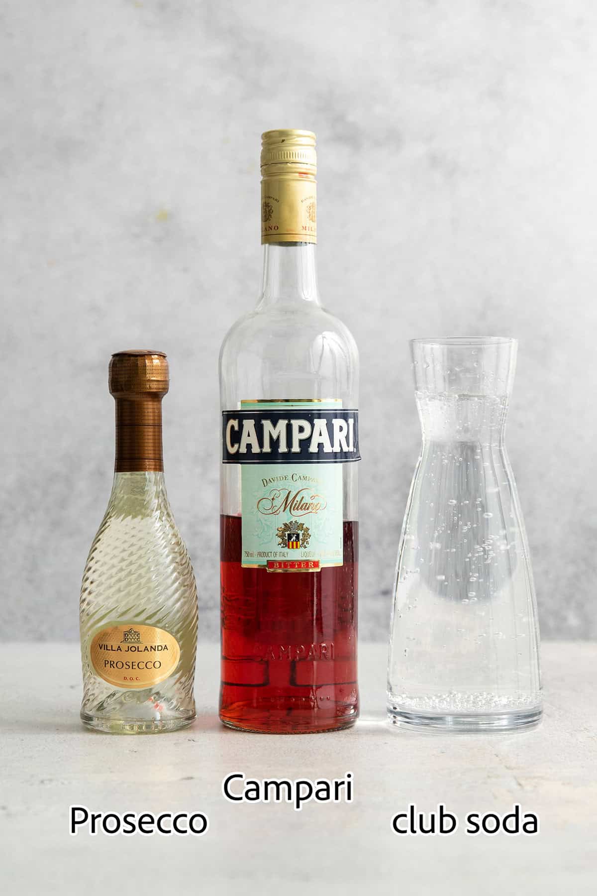 This refreshing, ruby-red Campari Spritz is a beautifully simple drink made with just 3 ingredients including campari and Prosecco. Ingredients for Campari spritz are shown: Campari, Prosecco, club soda.