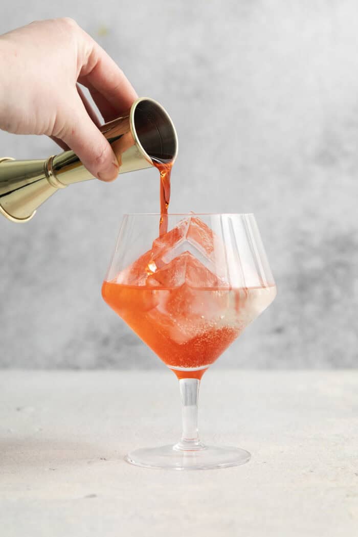 This refreshing, ruby-red Campari Spritz is a beautifully simple drink made with just 3 ingredients including campari and Prosecco. Campari is poured into the glass.