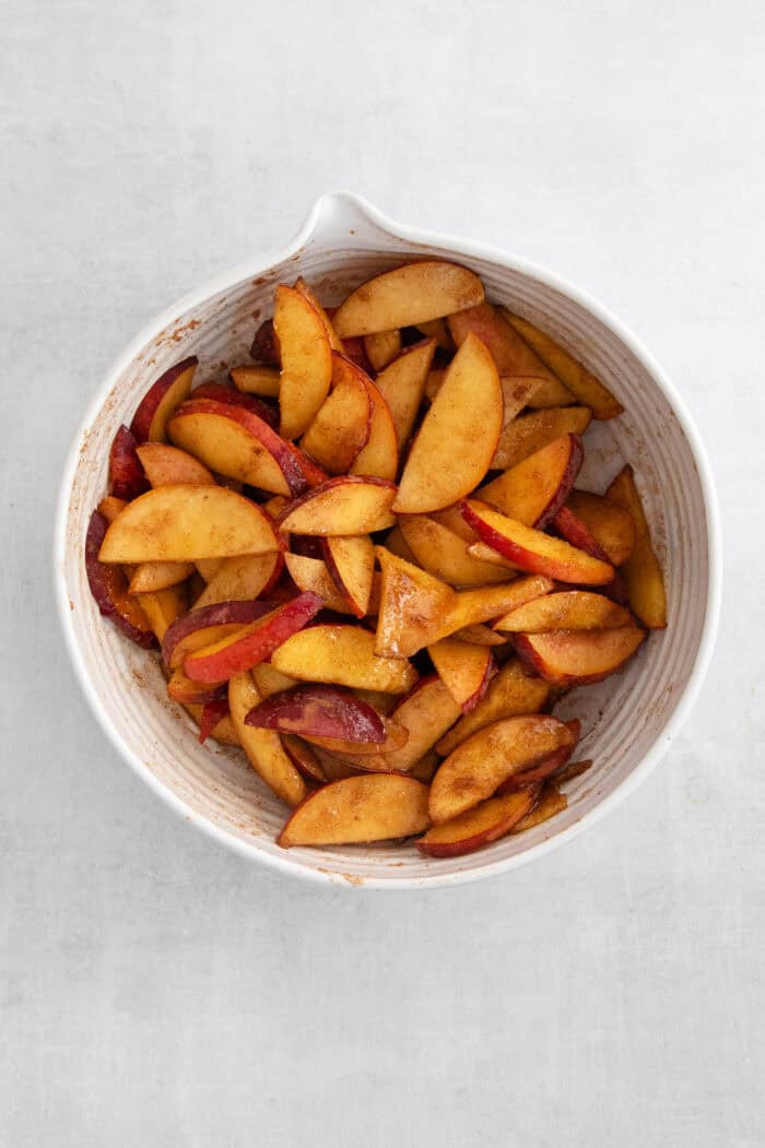 These Peach Bars feature a tender, buttery base topped with ripe, juicy peaches swirled with a touch of cinnamon. The filling ingredients are combined in a bowl.