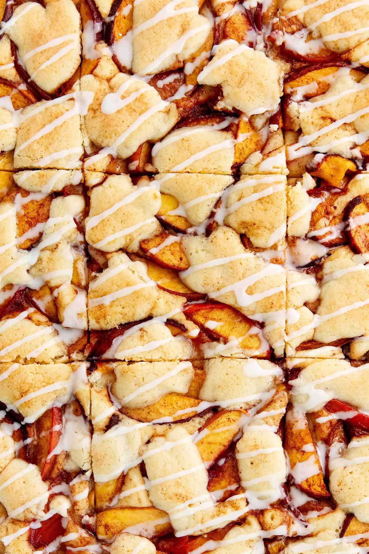These Peach Bars feature a tender, buttery base topped with ripe, juicy peaches swirled with a touch of cinnamon. Cuts are made in the peach bars.