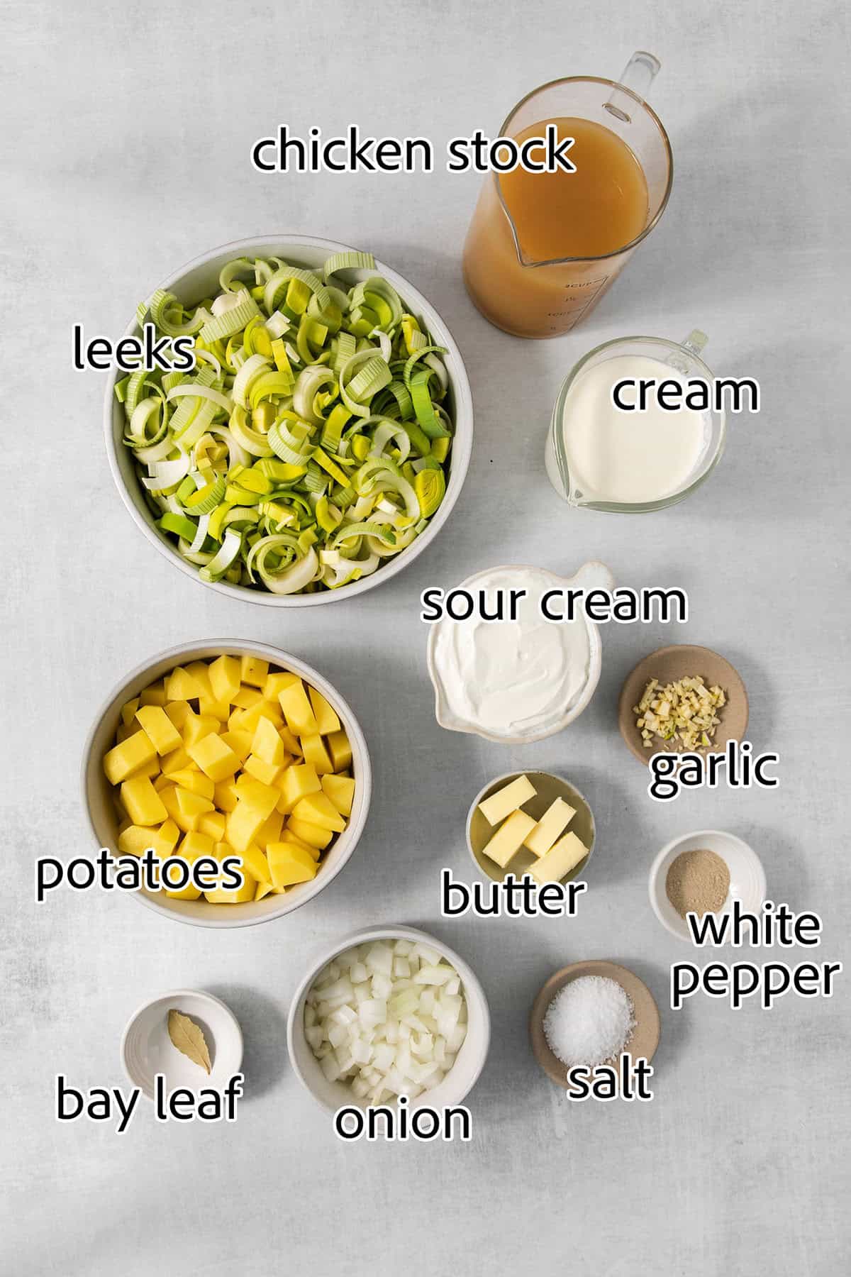 Ingredients to make vichyssoise are shown: potatoes, leeks, garlic, onion, salt and pepper, chicken broth, cream, sour cream, butter, bay leaf.