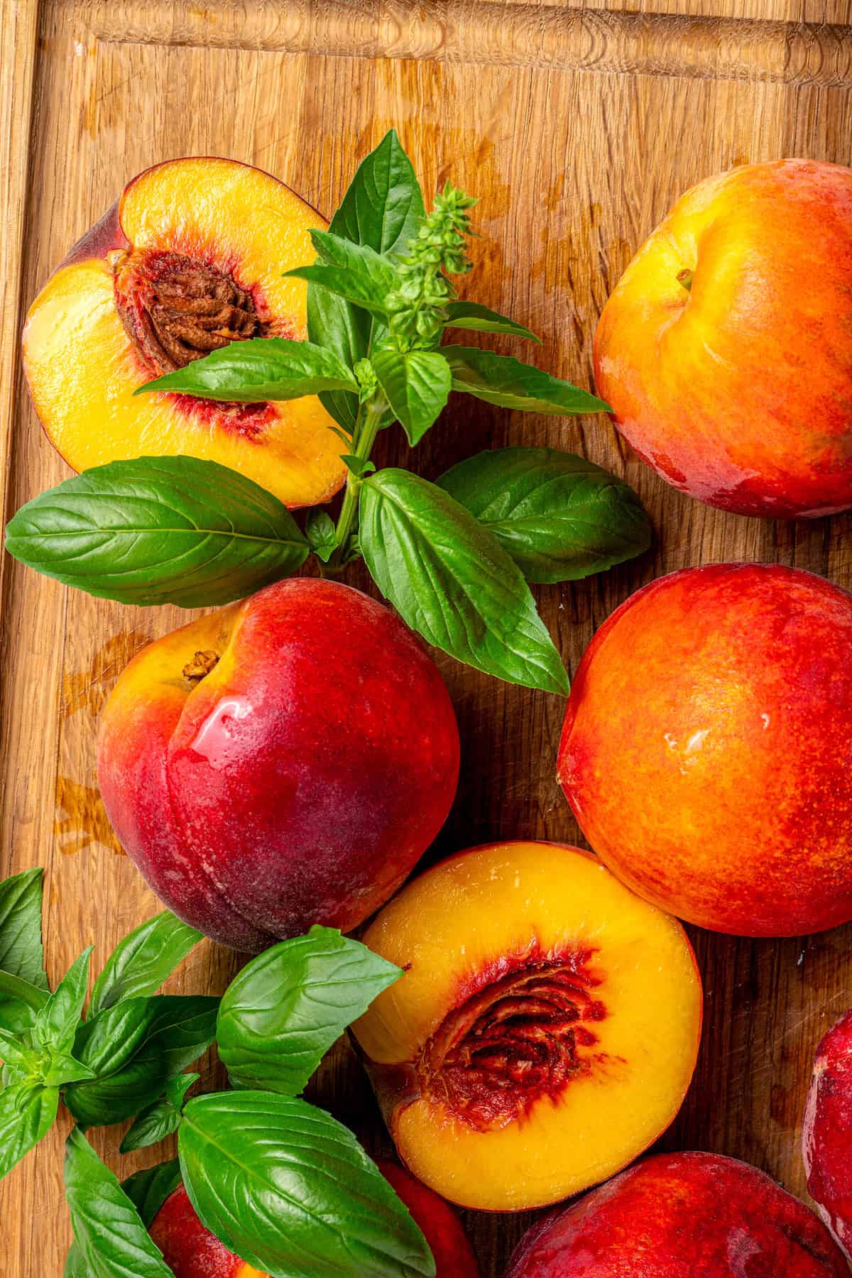 Sweet and juicy Grilled Peach Salad features lightly grilled peaches served with greens, cherry tomatoes, and fresh mozzarella. Peach halves are topped with fresh basil leaves.