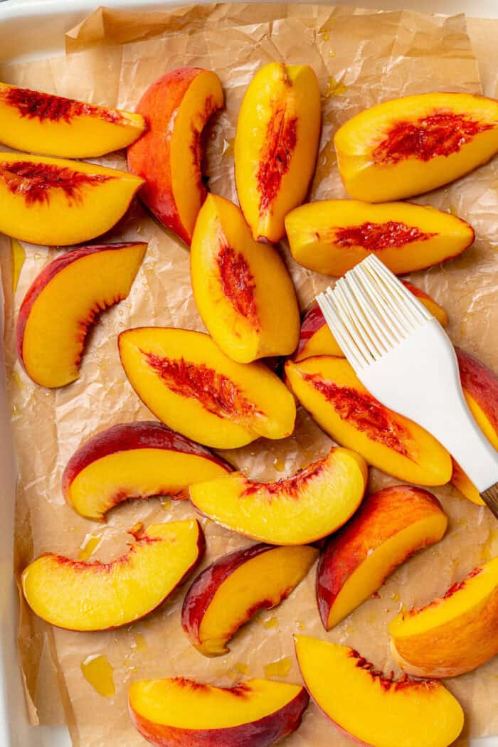 Sweet and juicy Grilled Peach Salad features lightly grilled peaches served with greens, cherry tomatoes, and fresh mozzarella. Oil is brushed onto fresh peach slices before grilling them.