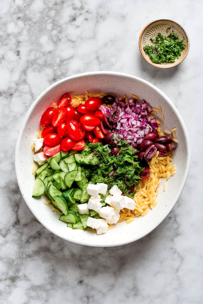 This easy Lemon Chicken Orzo Salad features fresh veggies, chicken, pasta, and a tangy lemon vinaigrette for a light yet filling meal. The vegetables are added to the orzo.