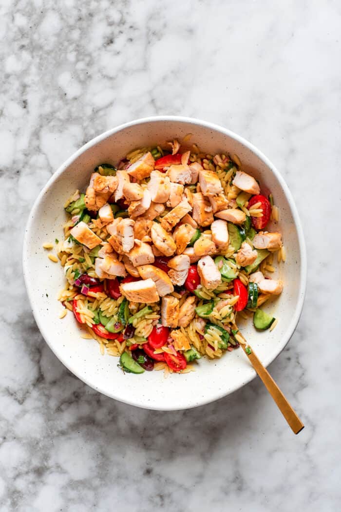 This easy Lemon Chicken Orzo Salad features fresh veggies, chicken, pasta, and a tangy lemon vinaigrette for a light yet filling meal. The chicken is added to the salad.