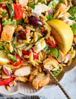 A serving spoon in a bowl of lemon chicken orzo pasta.