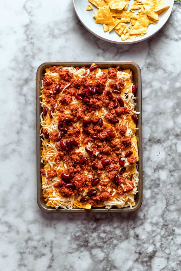 This Macho Nachos recipe features layers of crispy tortilla chips, melty cheese, and seasoned beef. Perfect for any casual gathering! More ground beef is added.