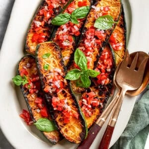 overhead photo of seared and roasted zucchini with fresh tomato sauce