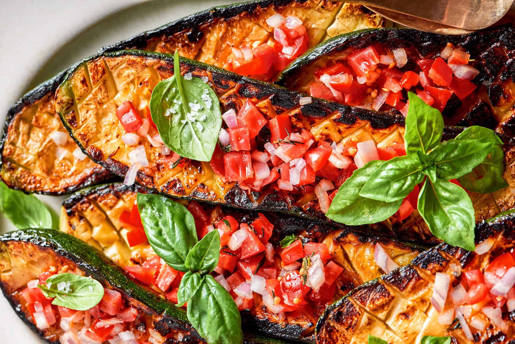 a platter of seared and roasted zucchini with fresh tomato sauce