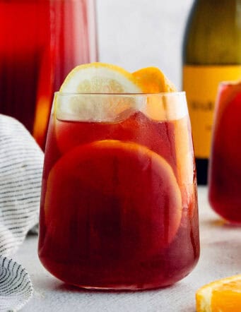 A glass of tinto de verano with a bottle of wine behind it.